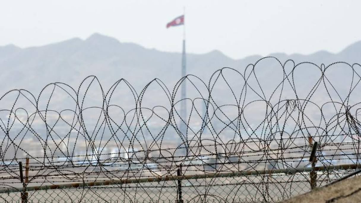 Un drapeau nord-coréen flotte derrière des barbelés délimitant la zone démilitarisée à la frontière entre la Corée du Nord et la Corée du Sud.

