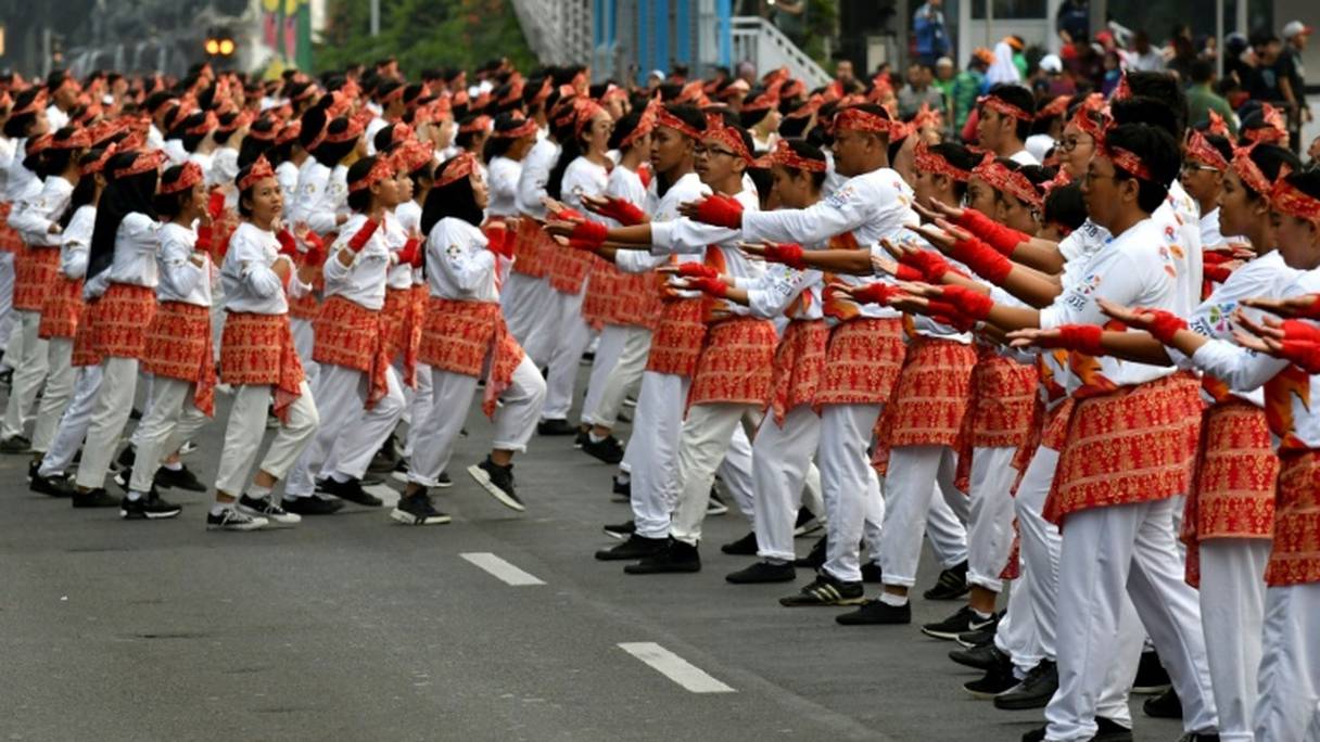 Des danseurs indonésiens,, habillés en blanc et rouge aux couleurs du drapeau national, interprètent la danse folklorique "poco poco", le 5 août 2018 à Jakarta.
