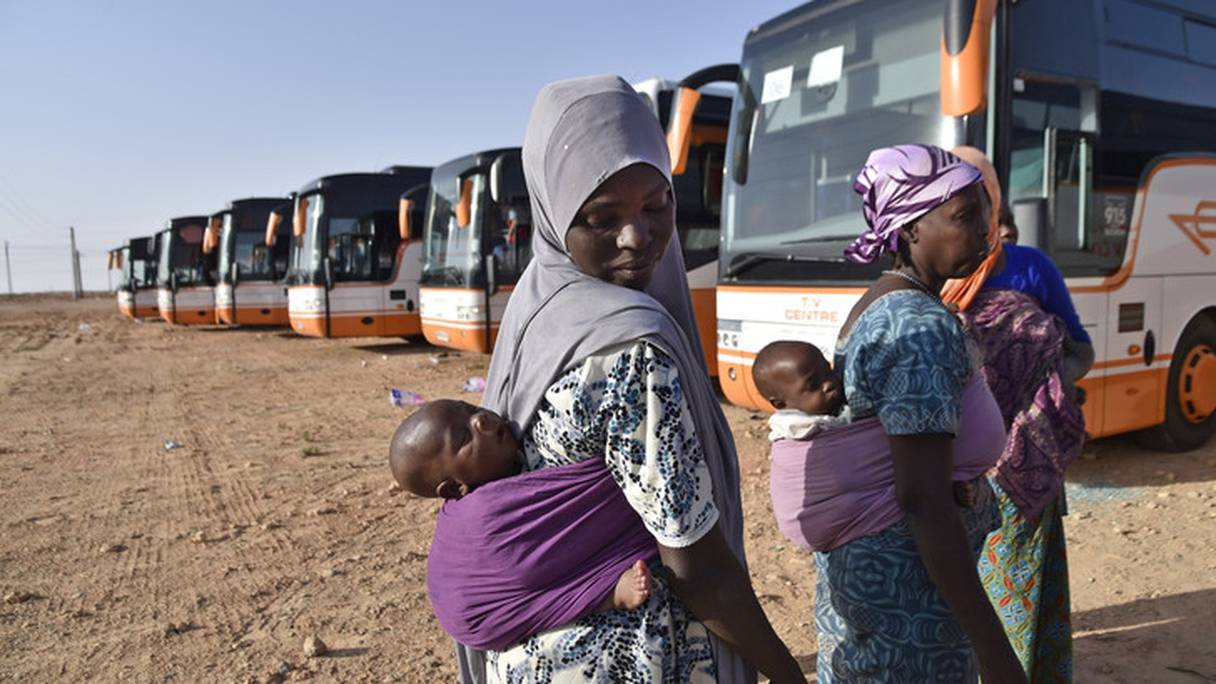 Des migrants africains en cours d'expulsion font un arrêt dans le désert à 200 km au nord de la ville algérienne de Tamanrasset lors de leur rapatriement en bus au Niger le 30 juin 2018.
