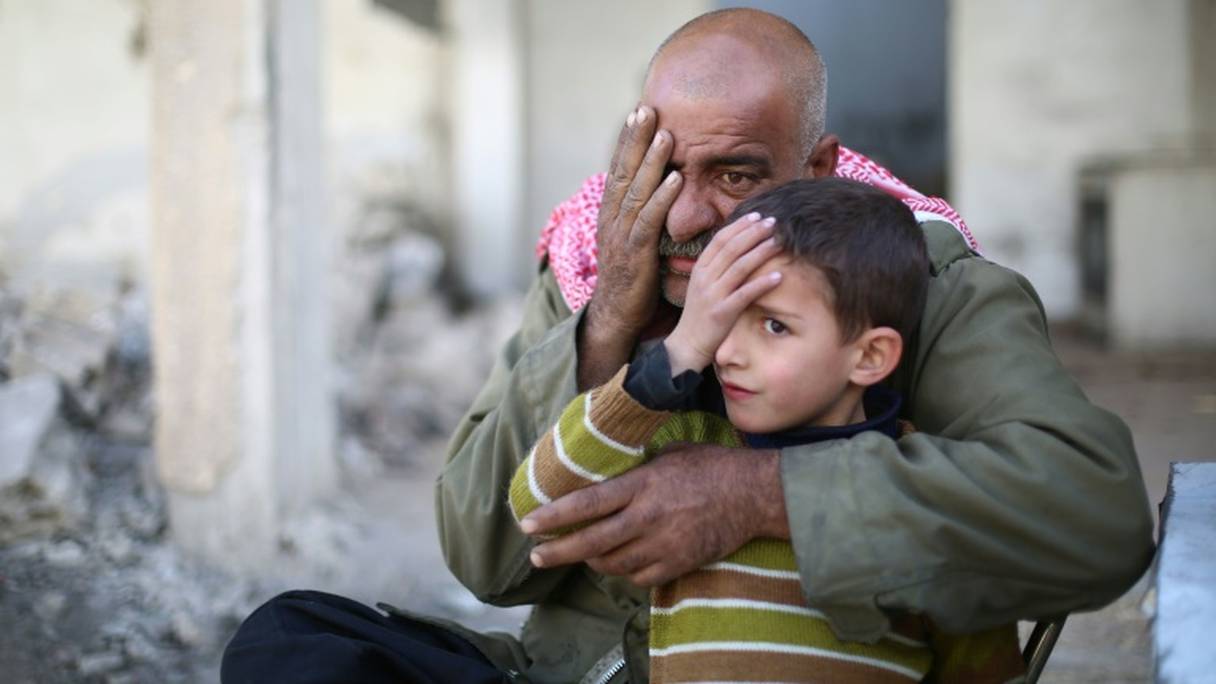Un vieil homme et un enfant cachent un œil dans la ville rebelle de Douma le 18 décembre 2017, en solidarité avec Karim, un bébé devenu borgne après un raid.
