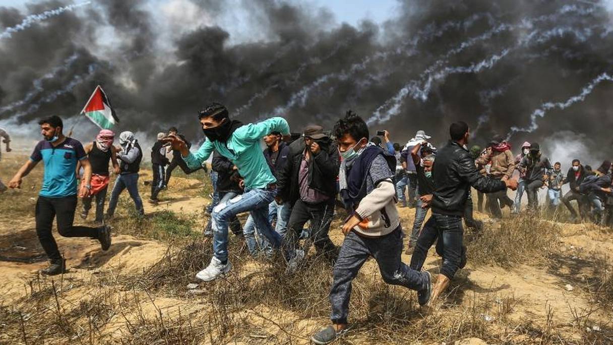 Des manifestants palestiniens fuient les gaz lacrymogènes de l'armée israélienne, le 27 avril 2018 à Gaza.
