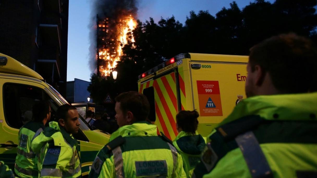 Des équipes de secours aux abords d'une tour d'habitation ravagée par un incendie, le 14 juin 2017 à Londres.
