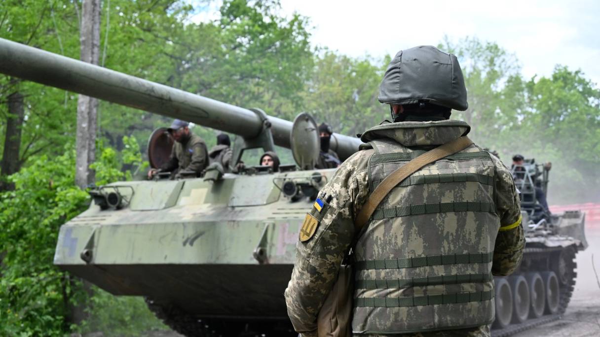 Un militaire ukrainien regarde un obusier automoteur sur une route dans la région de Kharkiv le 17 mai 2022, au cours de l'invasion russe de l'Ukraine.
