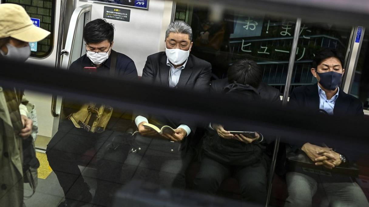 Des personnes portent un masque sanitaire, mesure préventive contre le Covid-19, à bord d'une rame du métro de Tokyo, dans la soirée du 17 novembre 2020.
