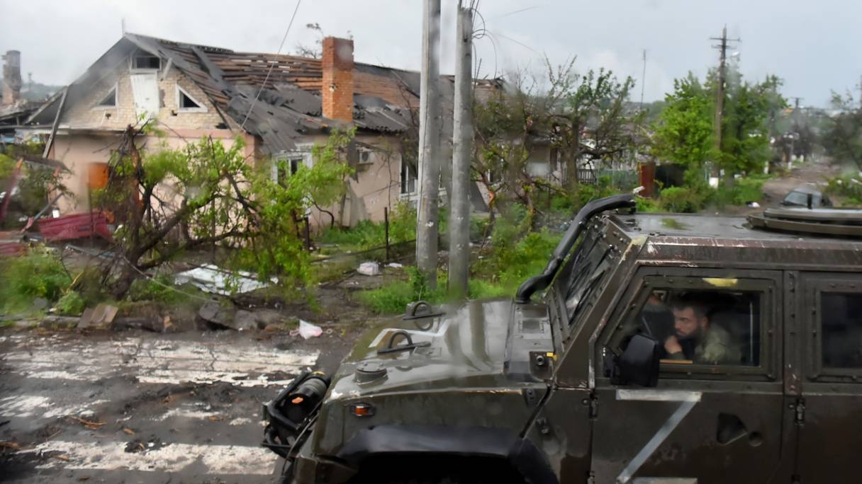 Un véhicule militaire russe passe devant des maisons détruites dans la ville portuaire ukrainienne de Marioupol, le 18 mai 2022.
