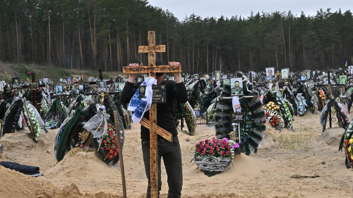 Un travailleur communal place une croix sur une tombe lors d'un enterrement dans un cimetière d'Irpin le 19 avril 2022, où il y a au moins trois rangées de nouvelles tombes pour les personnes tuées lors de l'invasion russe de l'Ukraine.
