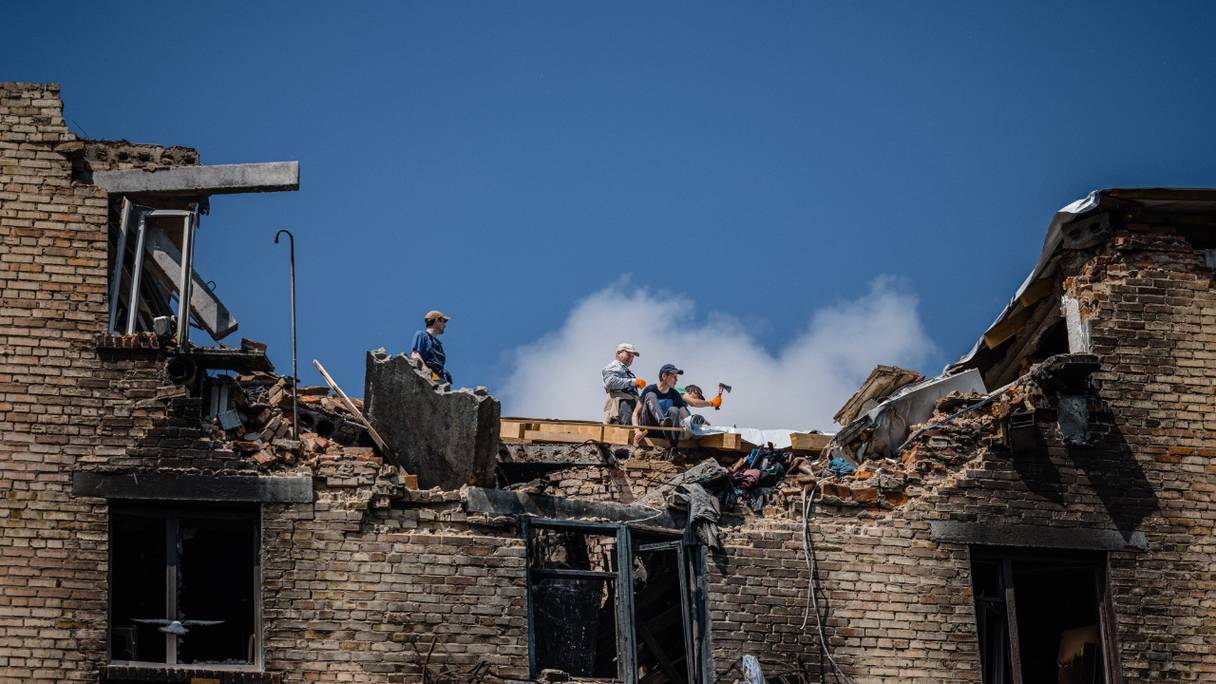 Des ouvriers réparent le toit brûlé d'un immeuble endommagé dans la ville de Makariv le 1er juin 2022, au cours de l'invasion russe de l'Ukraine.
