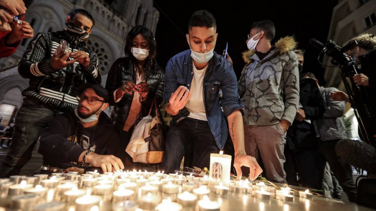 Des personnes allument des bougies près de la basilique Notre-dame de l'Assomption, à Nice, jeudi 29 octobre 2020 au soir, en hommage aux trois victimes de l'attaque au couteau à l'intérieur de ce lieu de culte catholique. 
