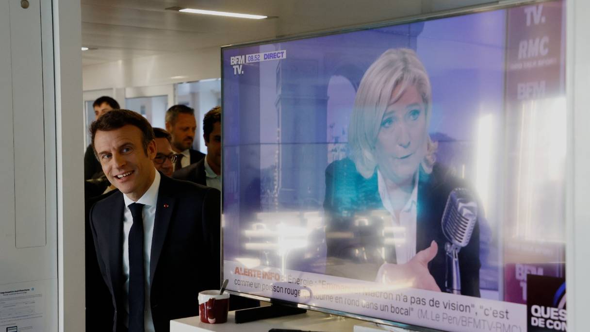 Le président français et candidat de La République en marche, Emmanuel Macron, visite le bureau de France Inter, à côté d'un écran de télévision affichant Marine Le Pen, la candidate du parti d'extrême-droite Rassemblement National, à Paris, le 4 avril 2022.
