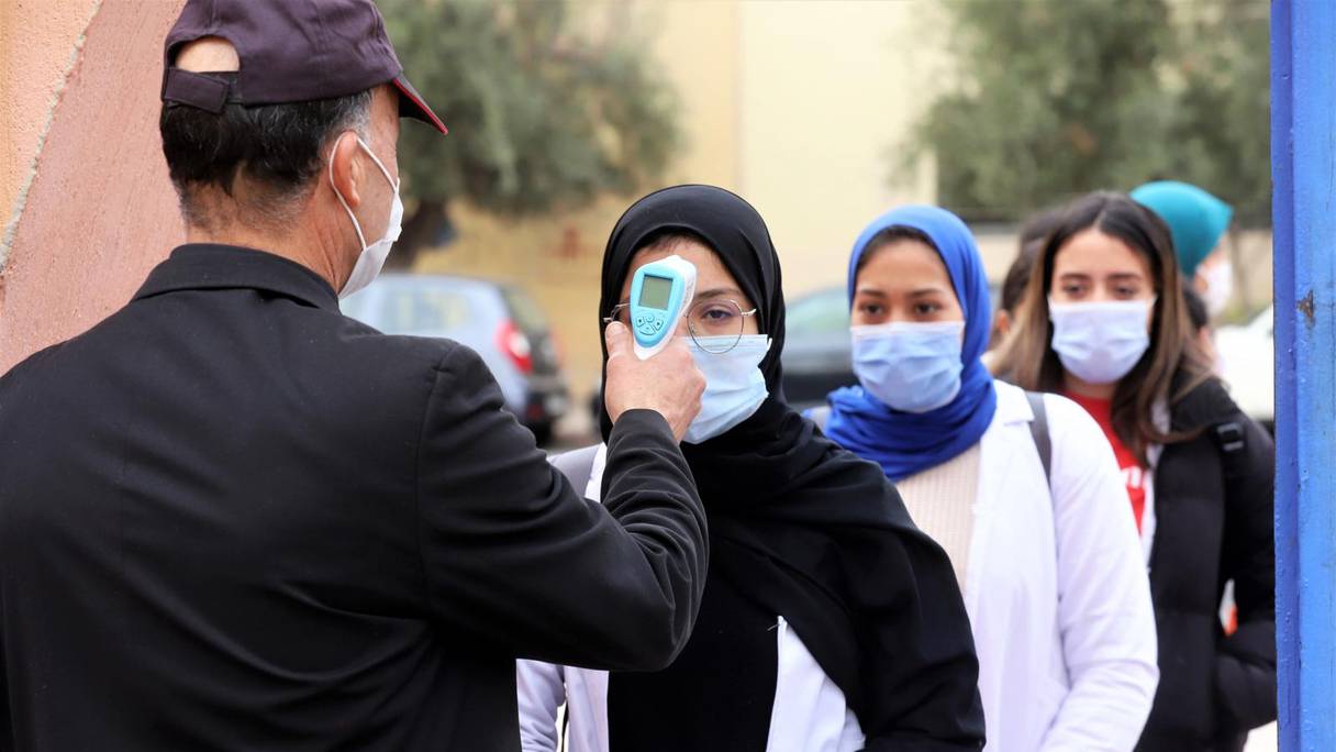 Un agent de sécurité prend la température des élèves à l'entrée du lycée secondaire qualifiant Hassan II, le 11 janvier 2022, à Marrakech, afin de faire détecter d'éventuels cas de Covid-19.
