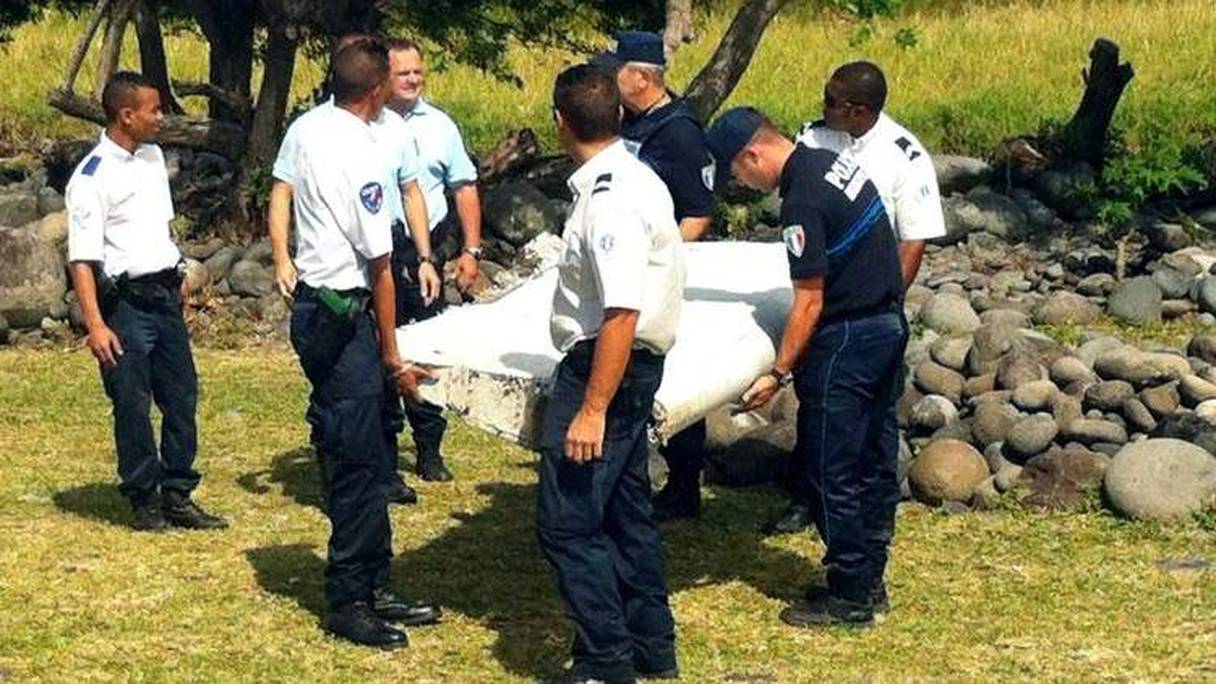 Des policiers transportent des débris d'un avion non identifié retrouvé au large de La Réunion, le 29 juillet 2015.
