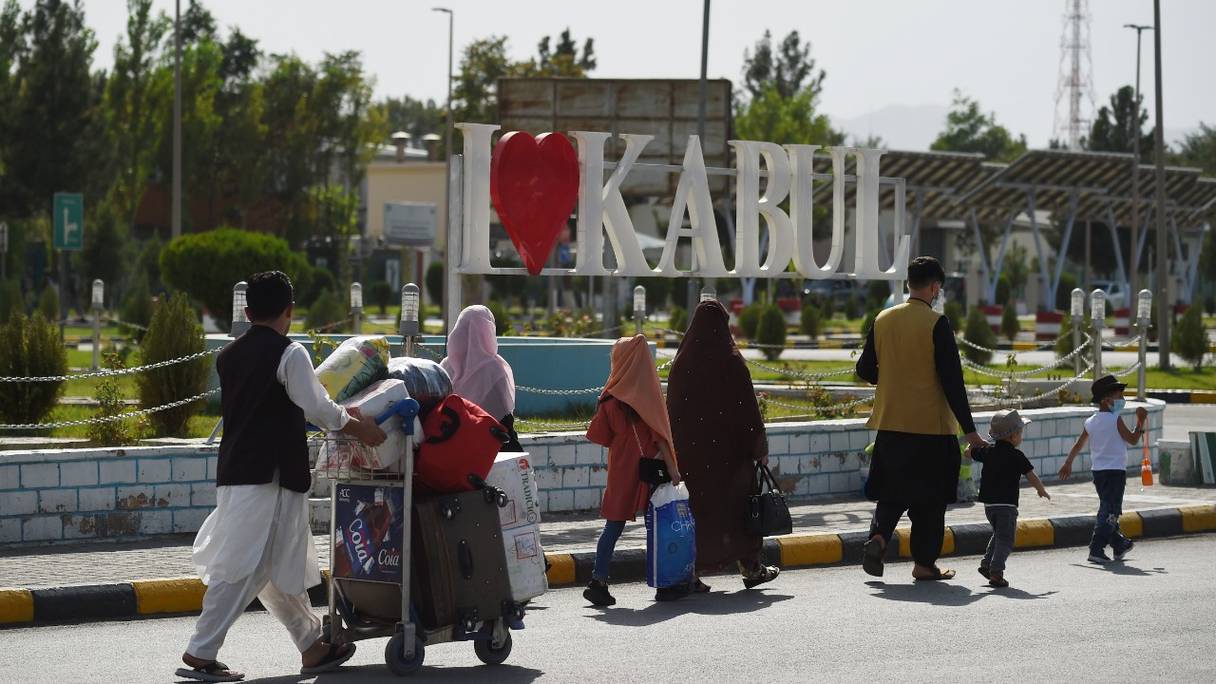 Des passagers afghans transportent leurs affaires à leur sortie du terminal domestique, à l'aéroport de Kaboul, le 8 août 2021.
