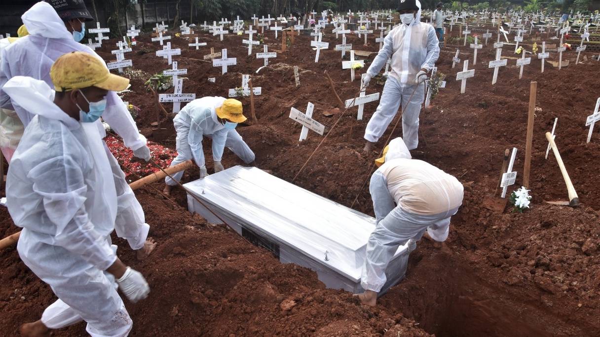 Des fossoyeurs enterrent le cercueil d'un homme décédé des suites du Covid-19 dans un cimetière de Bekasi, le 6 août 2021, alors que l'Indonésie franchit le sombre cap des 100 000 décès dus à la maladie.
