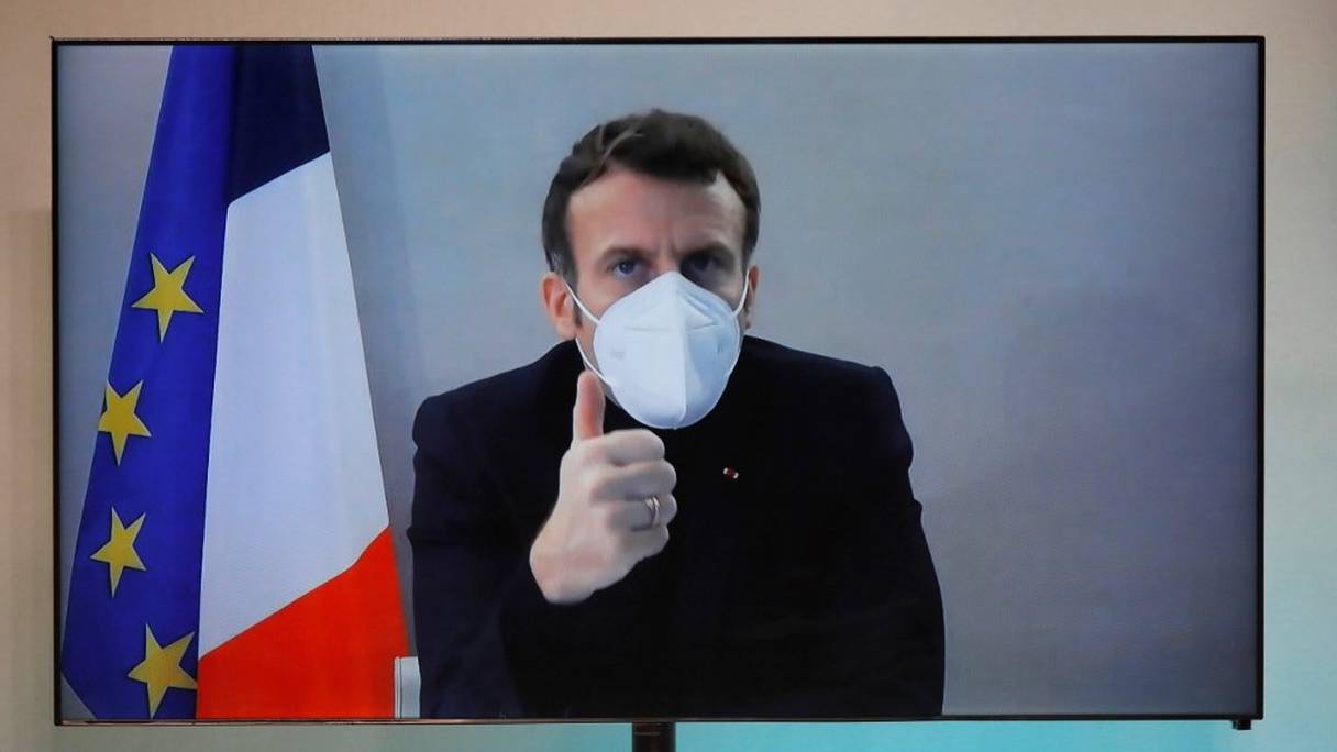 Le président français Emmanuel Macron, testé positif au Covid-19, apparaît sur un écran de télévision, lors d'une visioconférence organisée par le quai d'Orsay, le 17 décembre 2020, à Paris. 

