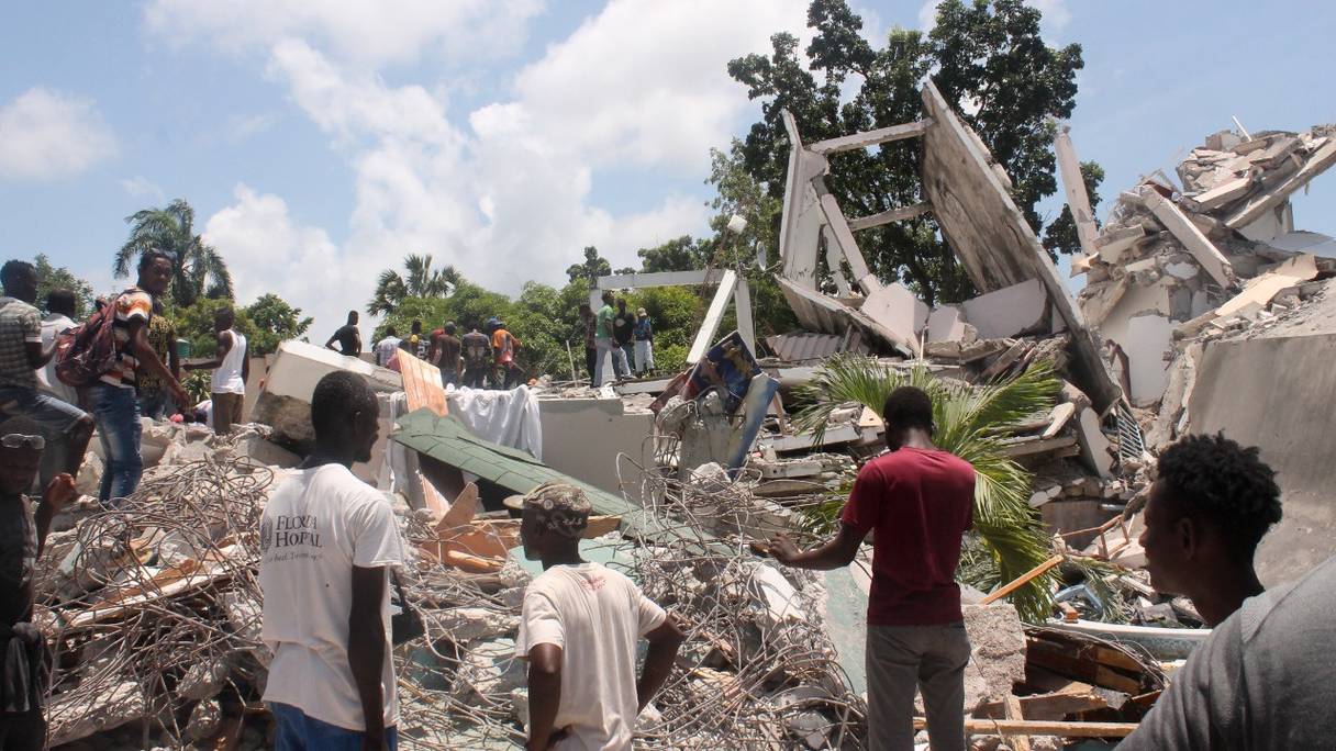 Des personnes fouillent les décombres d'un hôtel, après le tremblement de terre du 14 août 2021 aux Cayes, dans le sud-ouest d'Haïti, et tentent de trouver des survivants après ce puissant séisme de magnitude 7,2, qui a frappé Haïti, faisant au moins 304 morts.
