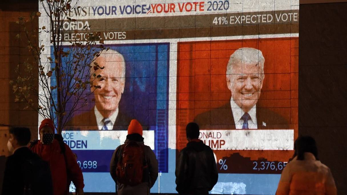 Des personnes regardent sur un écran géant le live des résultats du scrutin en Floride, au Black Lives Matter plaza, près de la Maison-Blanche, à Washington DC, le 3 novembre 2020. 
