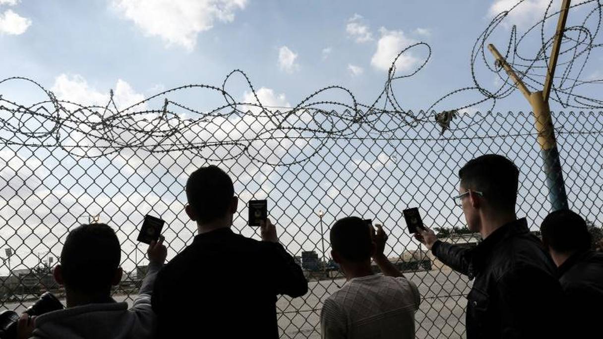 De jeunes Palestiniens montrent leur passeport alors qu'ils attendent de pouvoir traverser le point de passage de Rafah, avec l'Égypte.
