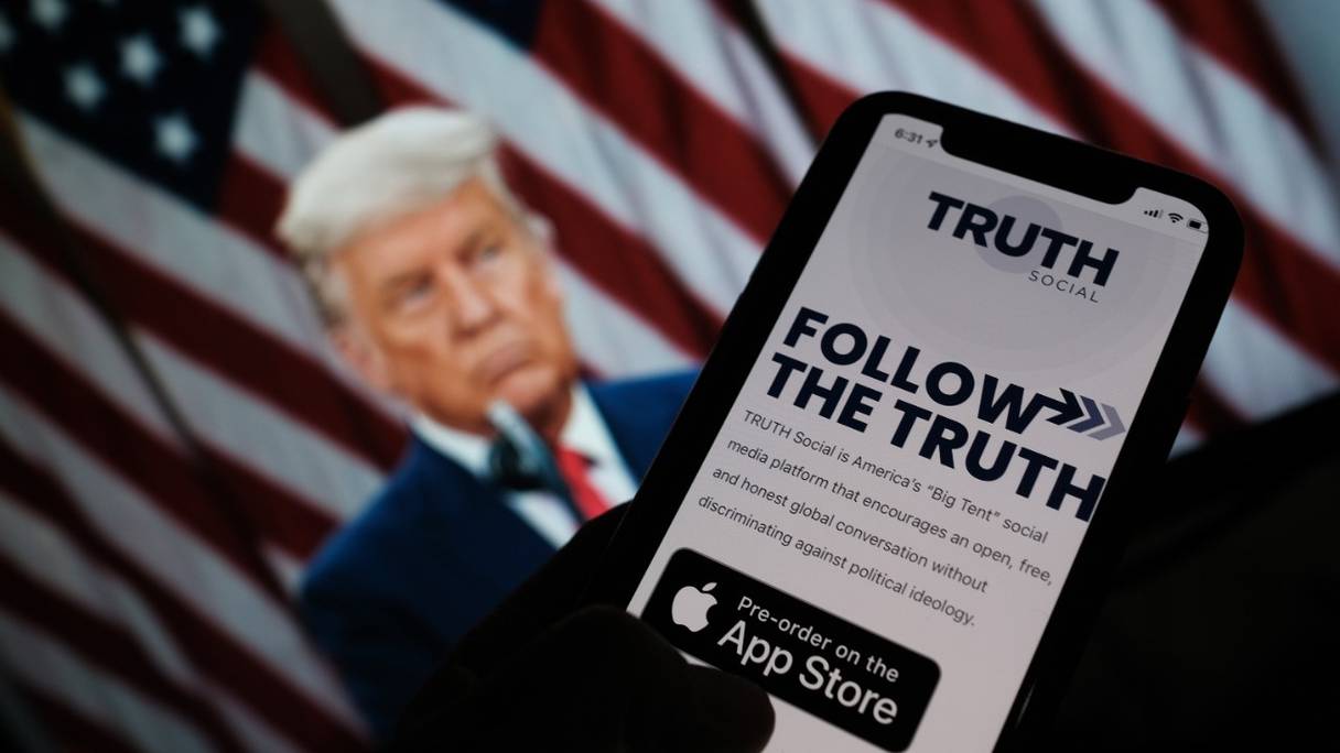 L'App Store apparaît sur un smartphone pour "Truth Social", avec une photo de Donald Trump sur un écran d'ordinateur en arrière-plan, à Los Angeles. L'ancien président américain a annoncé le 20 octobre son intention de lancer son propre réseau social.

