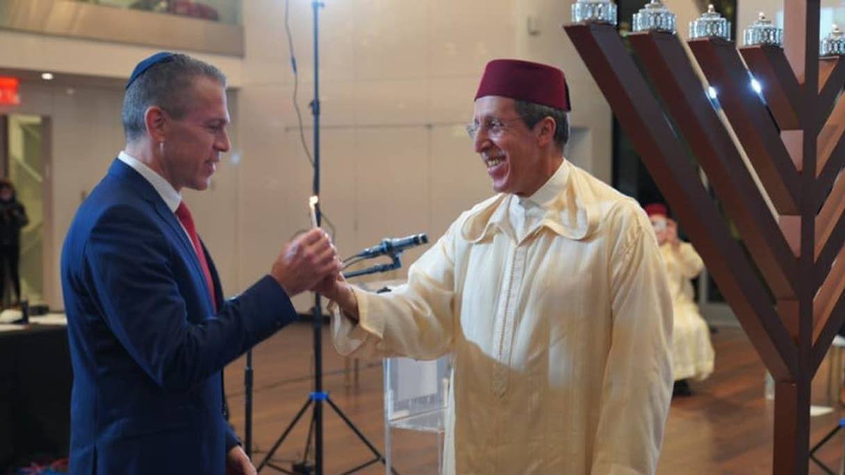 L’ambassadeur marocain allumant la huitième bougie du chandelier Hanoukkiah, en compagnie de son homologue israélien.

