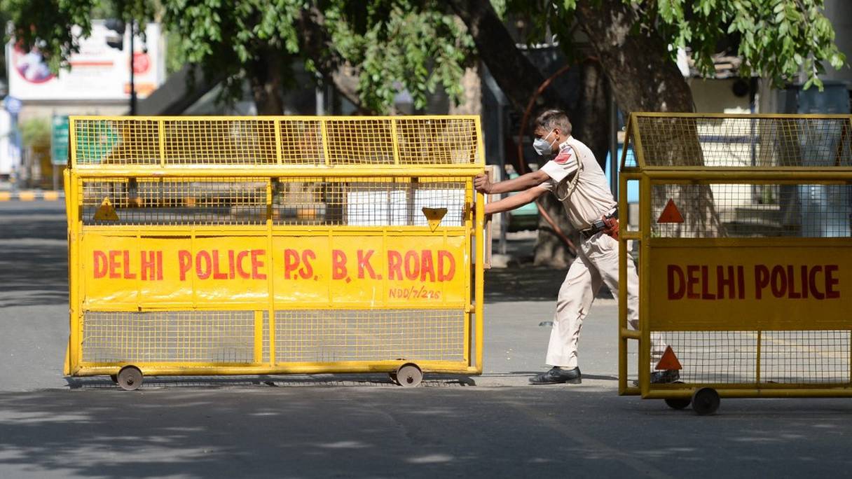 Un policier pousse une barrière à un point de contrôle routier lors d'un confinement imposé par le gouvernement dans le contexte de l'augmentation des cas de Covid-19, à New Delhi, le 12 mai 2021.
