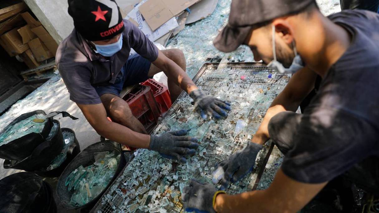 Des ouvriers trient le verre cassé lors de l'explosion au port de Beyrouth pour le recycler à Tripoli, ville portuaire du nord du Liban, le 25 août 2020. 
