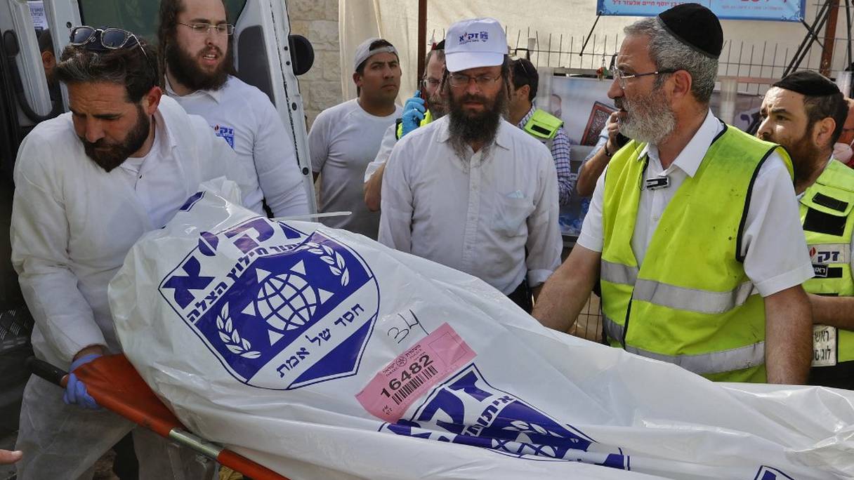 Les équipes de secours israéliennes transportent un sac mortuaire dans une ambulance le 30 avril 2021, sur les lieux d'une bousculade qui a eu lieu pendant la nuit lors d'un rassemblement religieux dans la ville de Meron, dans le nord d'Israël.
