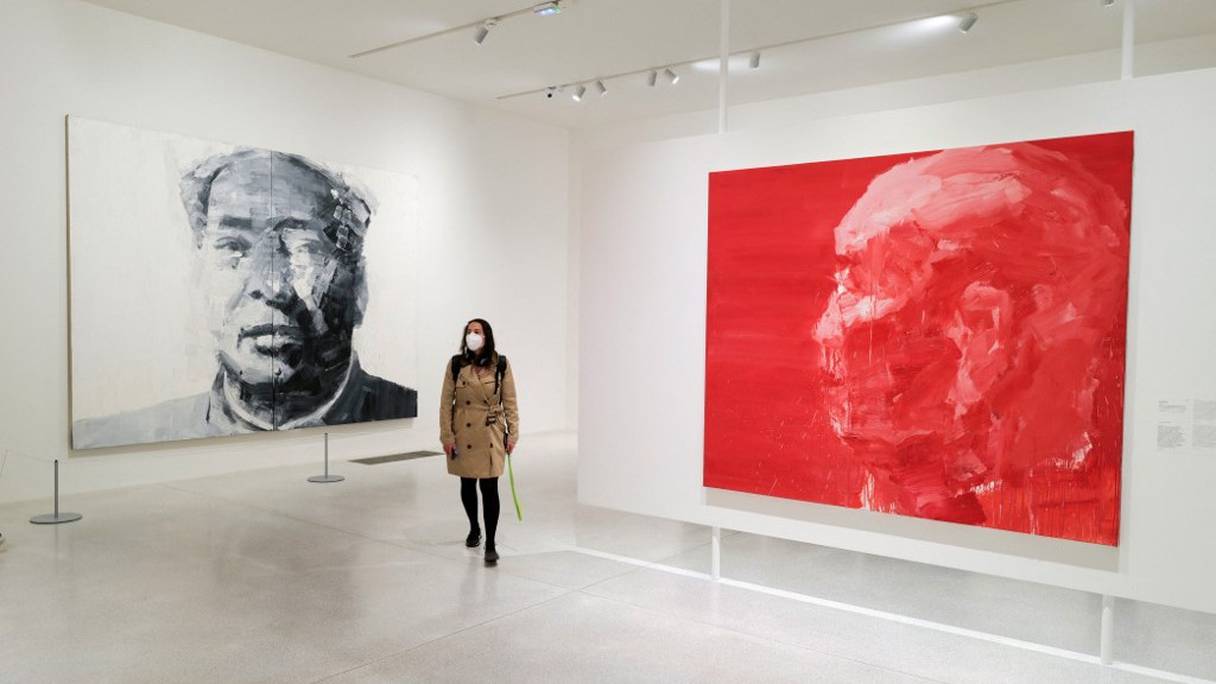Un visiteur passe devant "Portrait de Mao" (à gauche) et "L'homme le plus perspicace, père de l'artiste", de l'artiste franco-chinois Yan Pei-Ming, lors de l'exposition "Au nom du Père", au musée Unterlinden de Colmar, dans l'est de la France, le 31 mars 2021.
