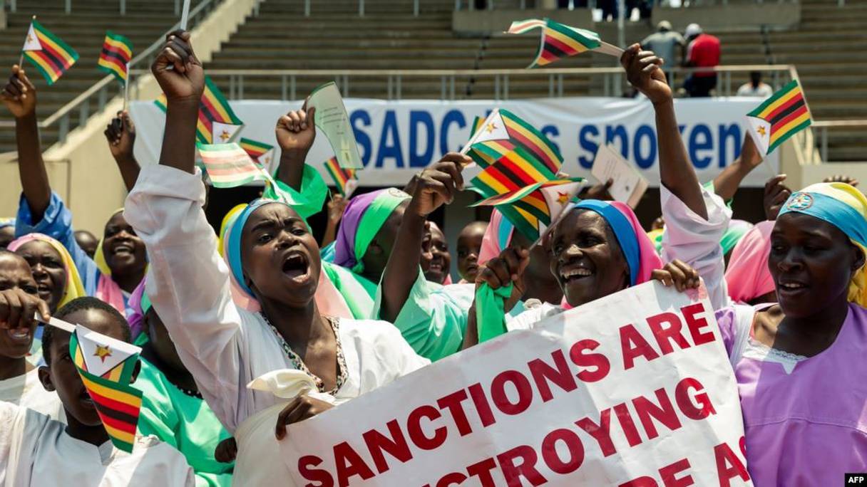 Des manifestants scandent des slogans et agitent le drapeau national du Zimbabwe au cours d'un rassemblement visant à dénoncer les sanctions économiques américaines et européennes, à Harare, le 25 octobre 2019.
