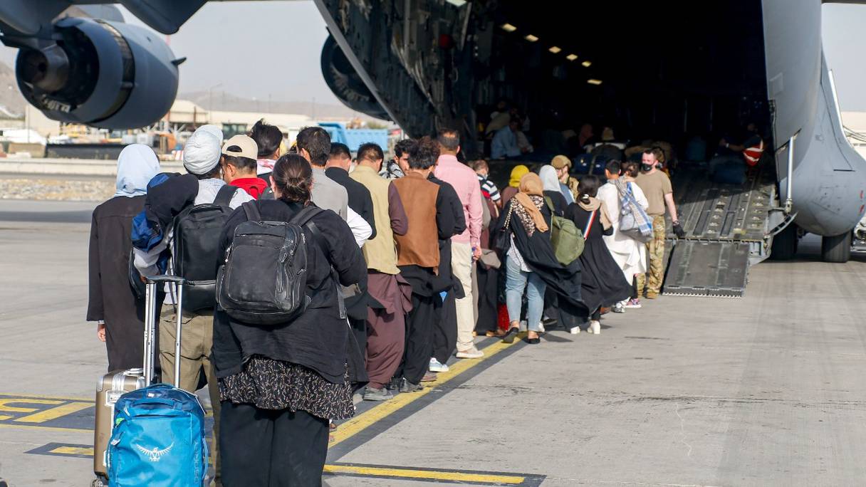 Des personnes partent d'Afghanistan, et montent à bord d'un C-17 Globemaster III lors d'une évacuation à l'aéroport international Hamid Karzai, à Kaboul, le 18 août 2021.
