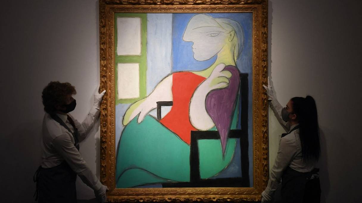 Des employés présentent "Femme assise près d'une fenêtre (Marie-Thérèse)'' du peintre espagnol Pablo Picasso lors d'un photocall à la maison de vente aux enchères Christie's, dans le centre de Londres, le 22 avril 2021. 
