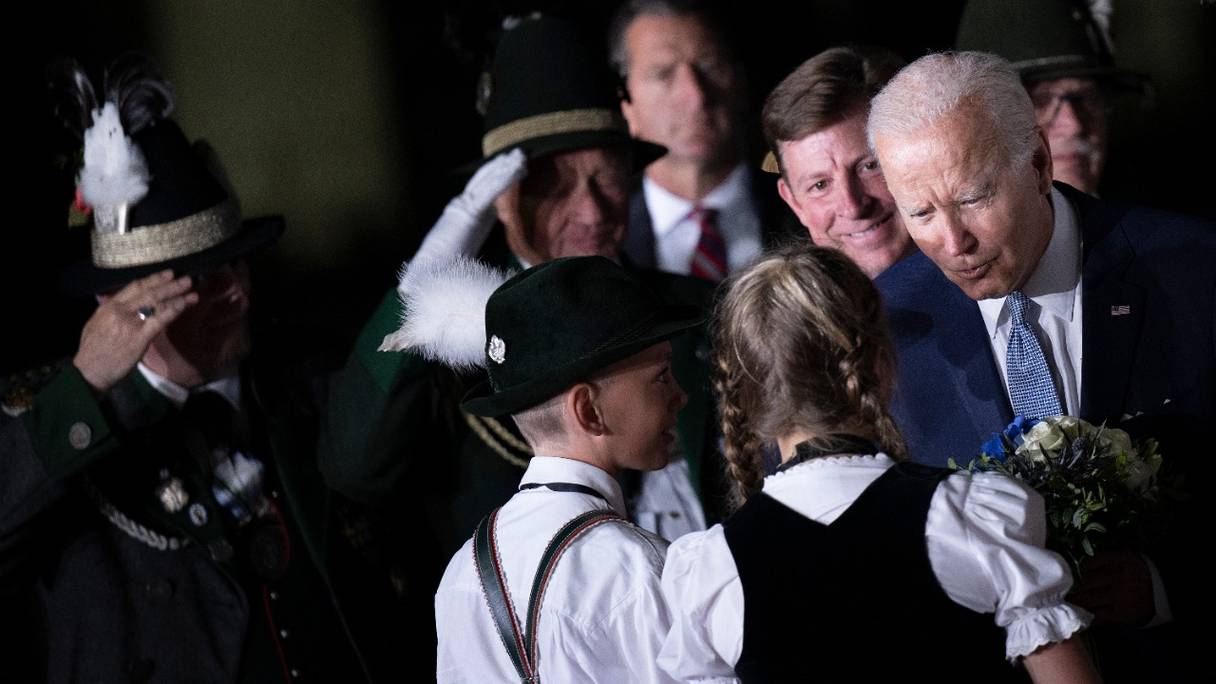 Le président américain Joe Biden est accueilli par des enfants portant des vêtements bavarois traditionnels, à son arrivée à l'aéroport Franz Josef Strauss de Munich, dans le sud de l'Allemagne, le 25 juin 2022, à la veille du sommet du G7.
