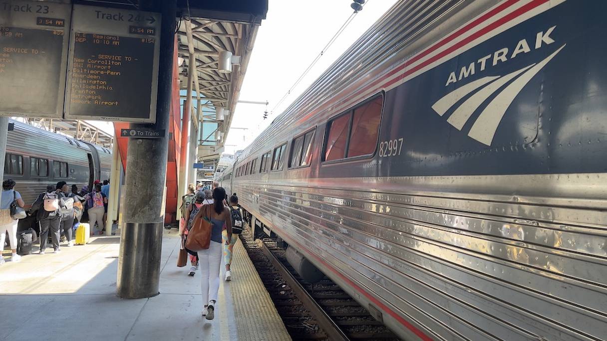 Des passagers marchent le long de la voie ferrée, où un train Amtrak est à quai, à la gare Union à Washington, DC, le 18 juillet 2021. 
