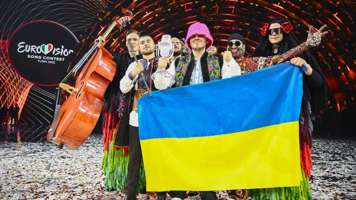 Les membres du groupe Kalush Orchestra posent sur scène avec le trophée du vainqueur et un drapeau ukrainien après avoir remporté au nom de l'Ukraine le concours Eurovision de la chanson 2022 le 14 mai 2022, au Pala Alpitour, à Turin.
