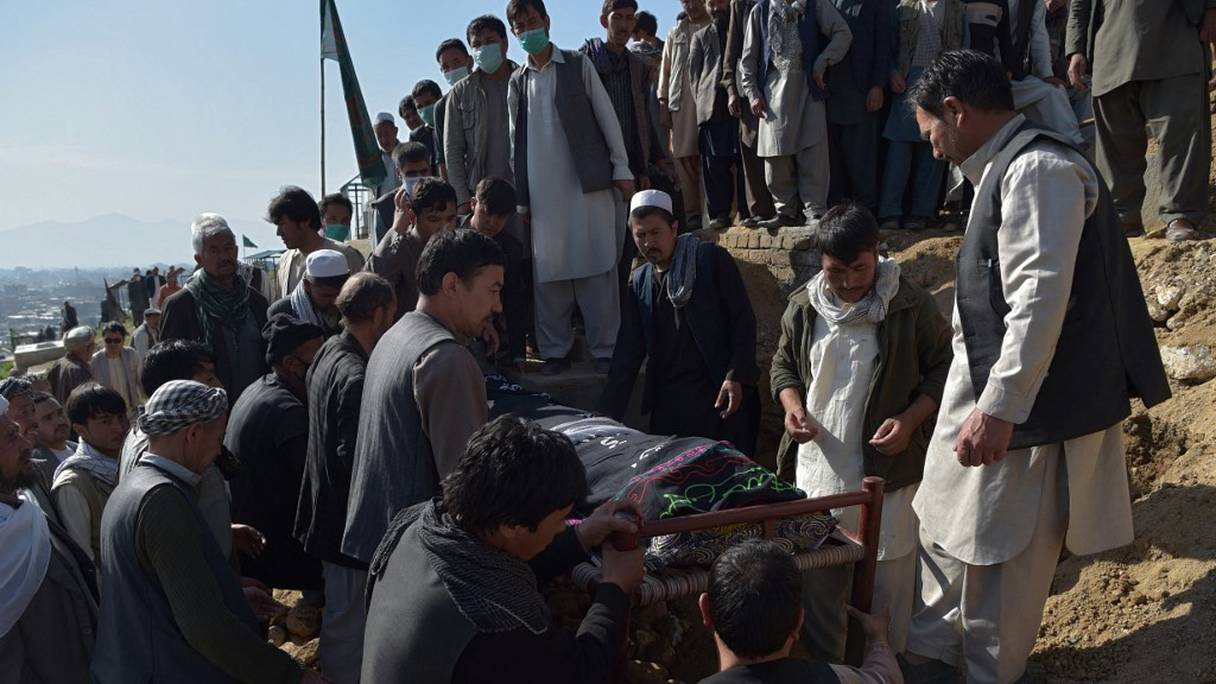 Des personnes en deuil et des proches enterrent une écolière, décédée hier lors de multiples explosions devant une école pour filles, dans la banlieue de Kaboul, le 9 mai 2021. 
