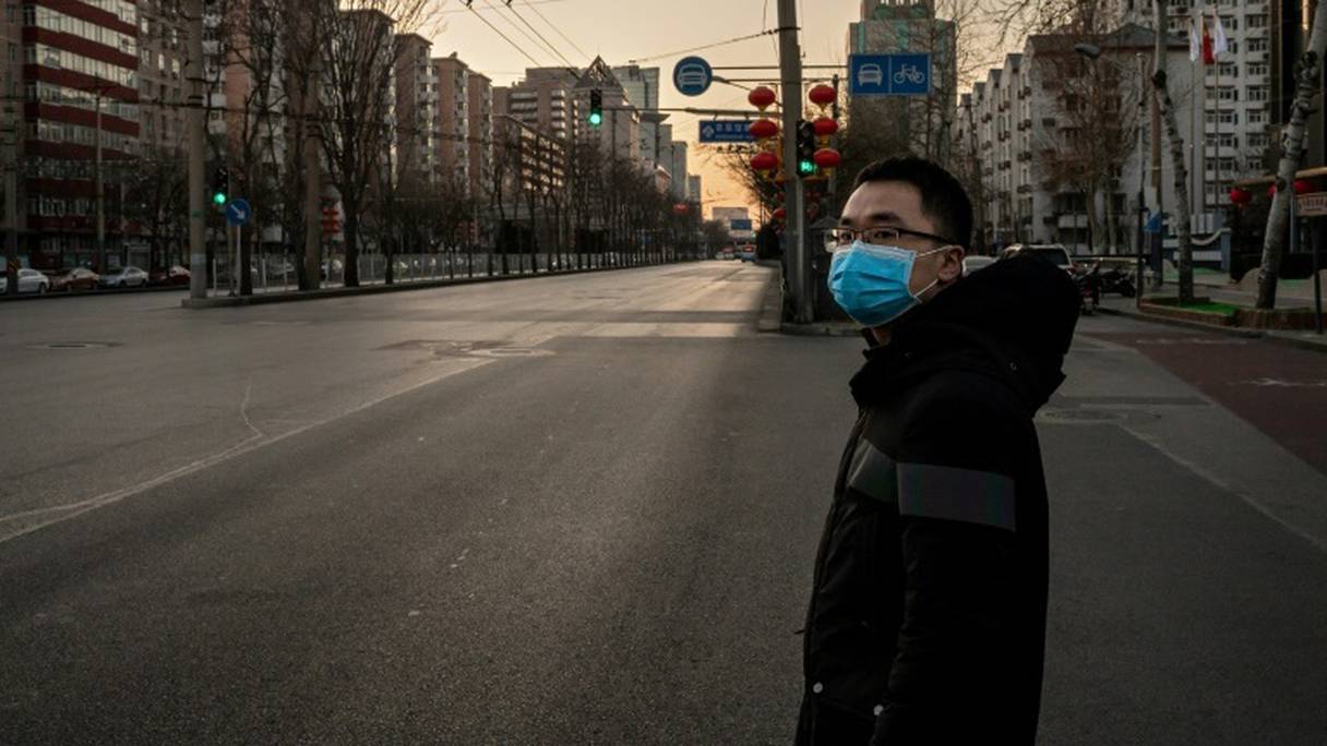 Un homme avec un masque s'apprête à tyraverser une artère de Pékin, désertée, le 31 janvier 2020.
