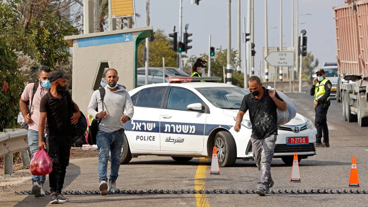 Des travailleurs palestiniens traversent une herse à un poste de contrôle dans le nord d'Israël près de la ville cisjordanienne de Jénine, le 12 septembre 2021.
