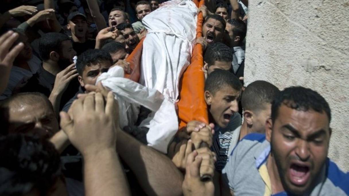 Des Palestiniens portent le corps de l'un des trois membres du Hamas tués par les frappes israéliennes. 
