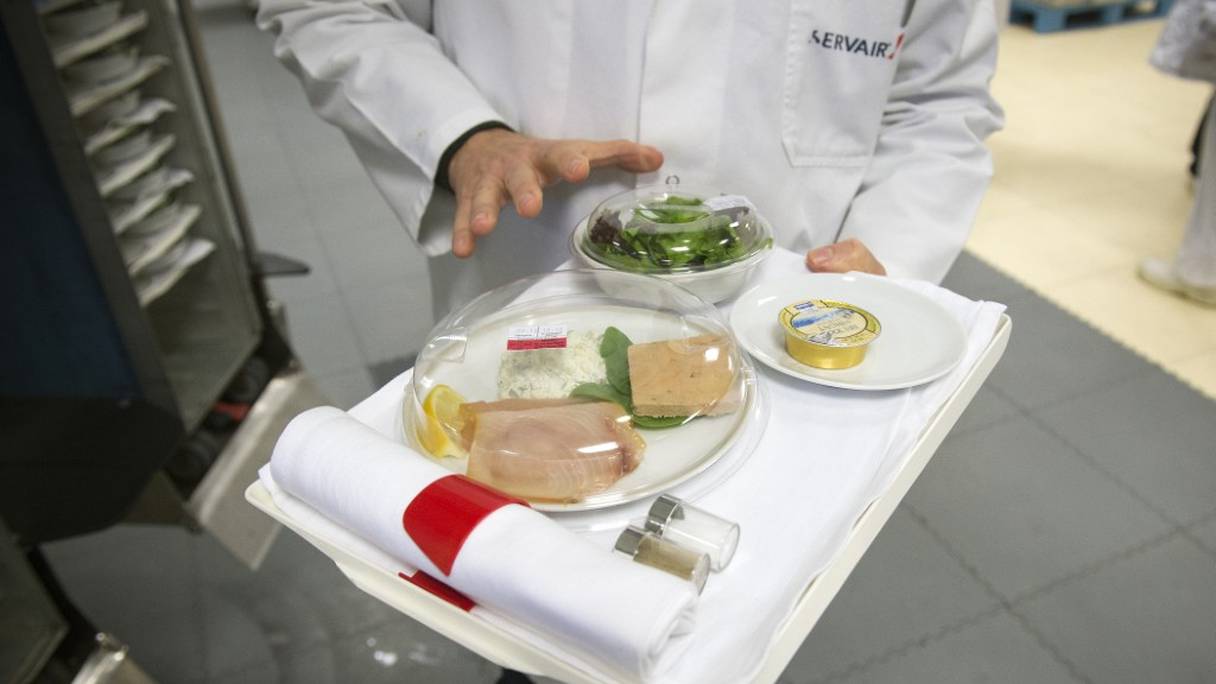Cette photo prise le 8 décembre 2014 montre un employé tenant un plateau-repas dans l'usine de la société de restauration aérienne Servair à l'aéroport de Paris Roissy - Charles de Gaulle.
