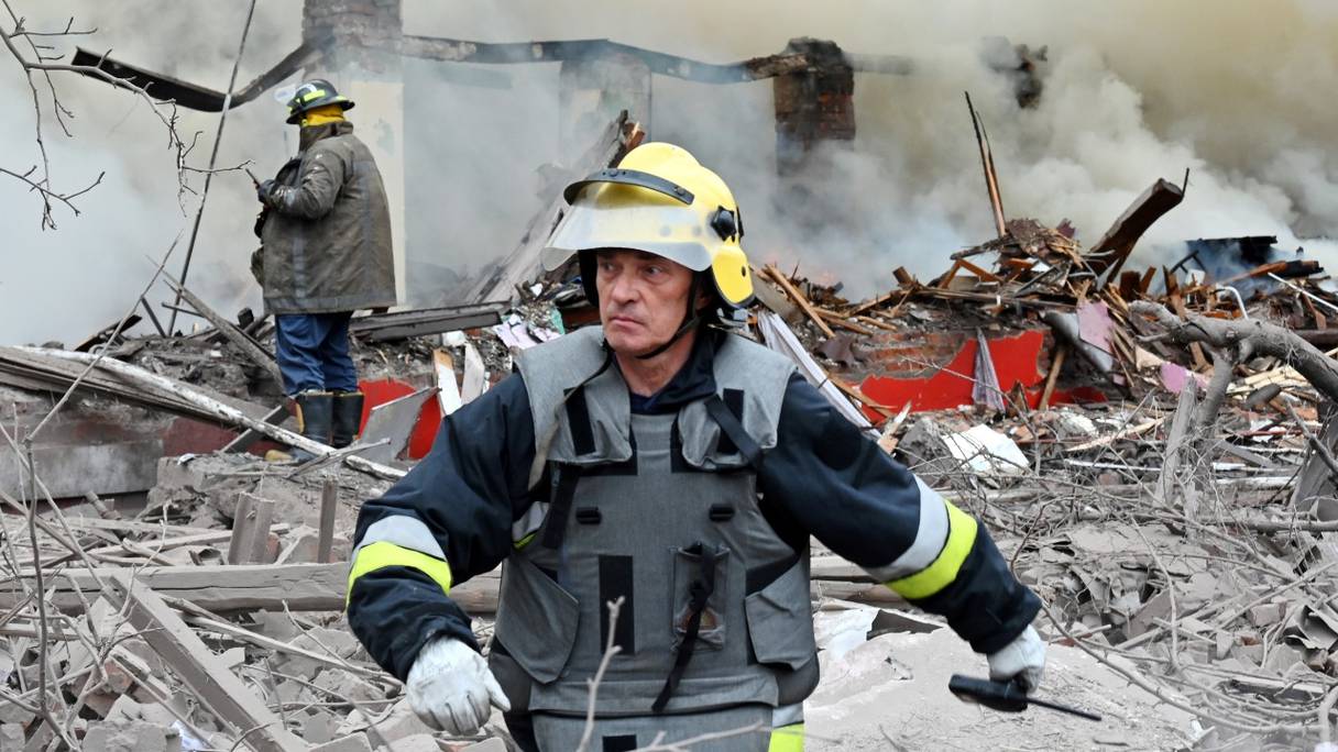 Un pompier marche alors que d'autres tentent d'éteindre un incendie après qu'un missile a touché un bâtiment à la périphérie de Kharkiv, le 12 avril 2022.
