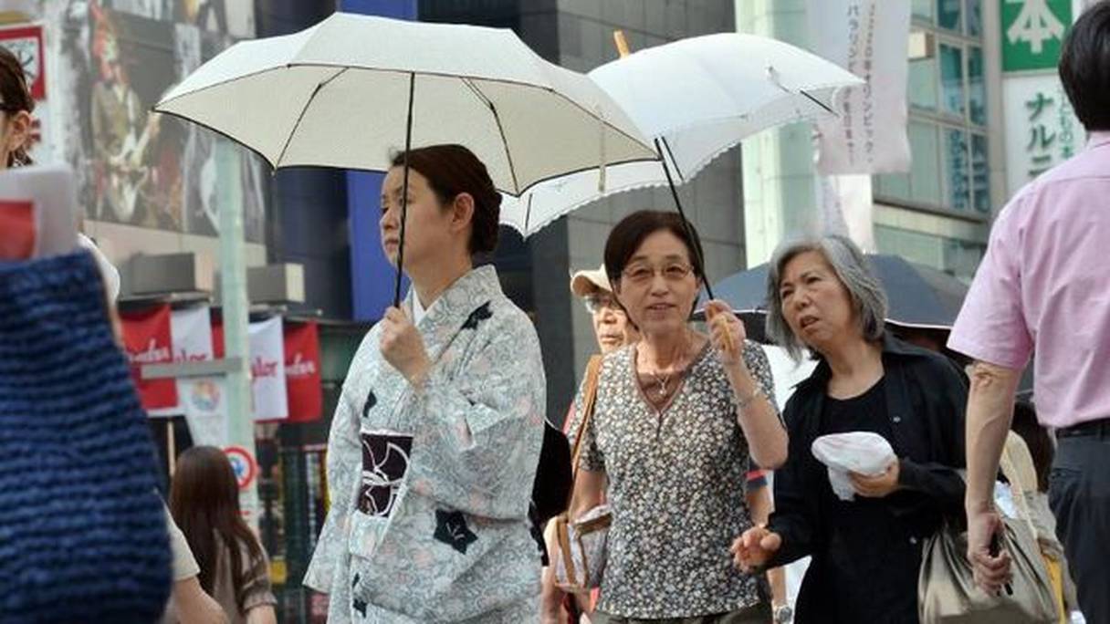 Des Japonais se protègent du soleil à Tokyo.
