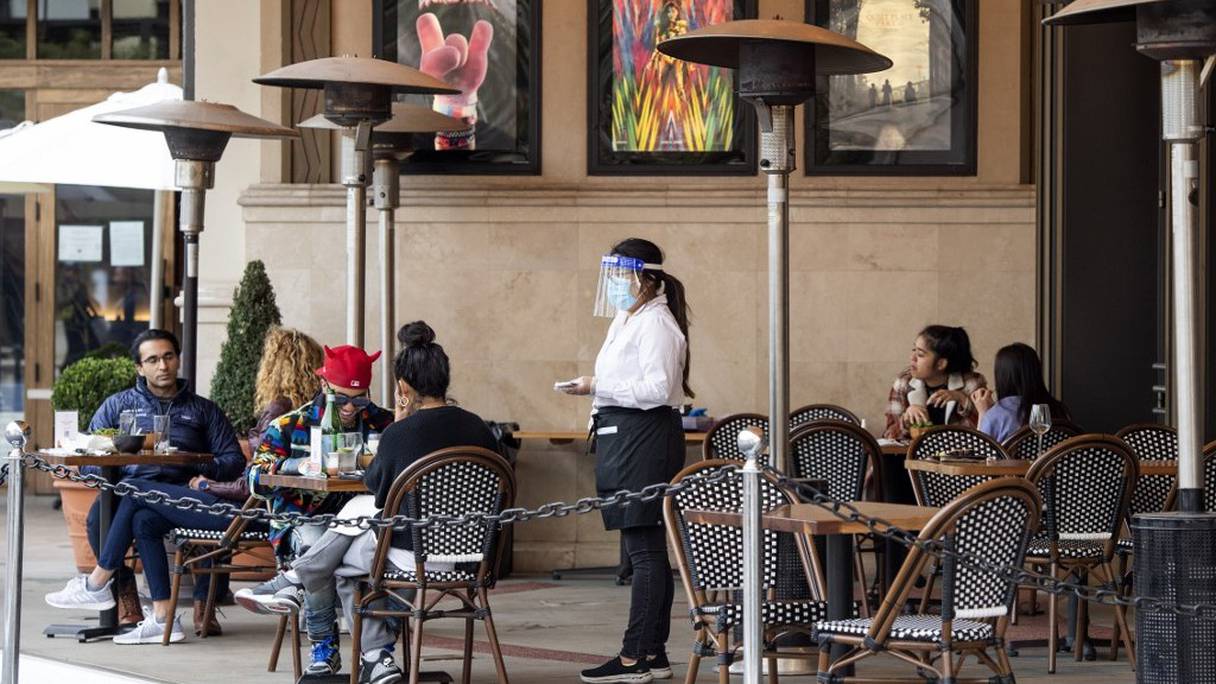 Une serveuse prend les commandes de clients à la terrasse d'un restaurant, le 28 janvier 2021, à Los Angeles, en Californie.
