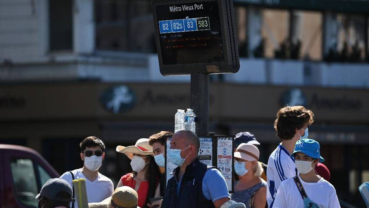 Des personnes portant des masques attendent à un arrêt de bus sur le Vieux Port, le 26 août 2020 à Marseille, dans le sud de la France. 
