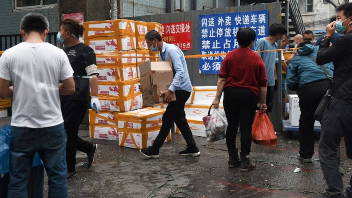 Des Chinois transportent des marchandises en dehors du marché aux fruits de mer de Jinshen, fermé pour désinfection, le 13 juin 2020 à Pékin.
