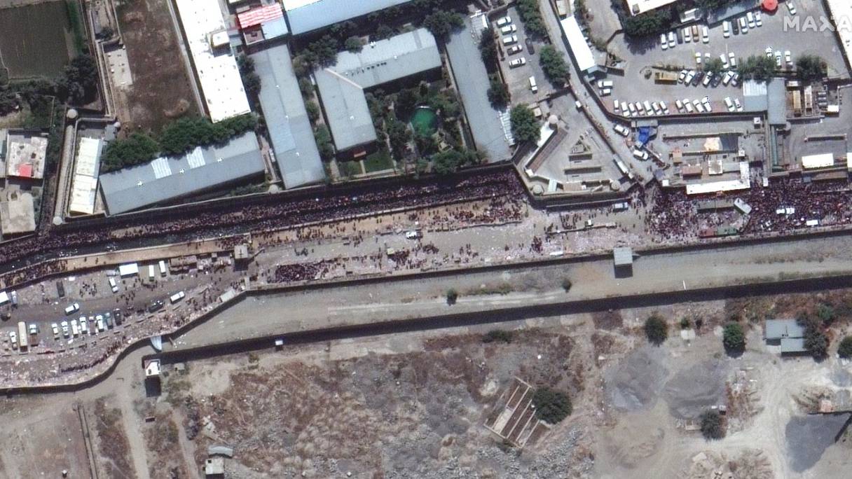 Cette photo prise d'un satellite montre une immense foule le long du bord est de l'aéroport international Hamid Karzai de Kaboul, en Afghanistan, le 23 août 2021.
