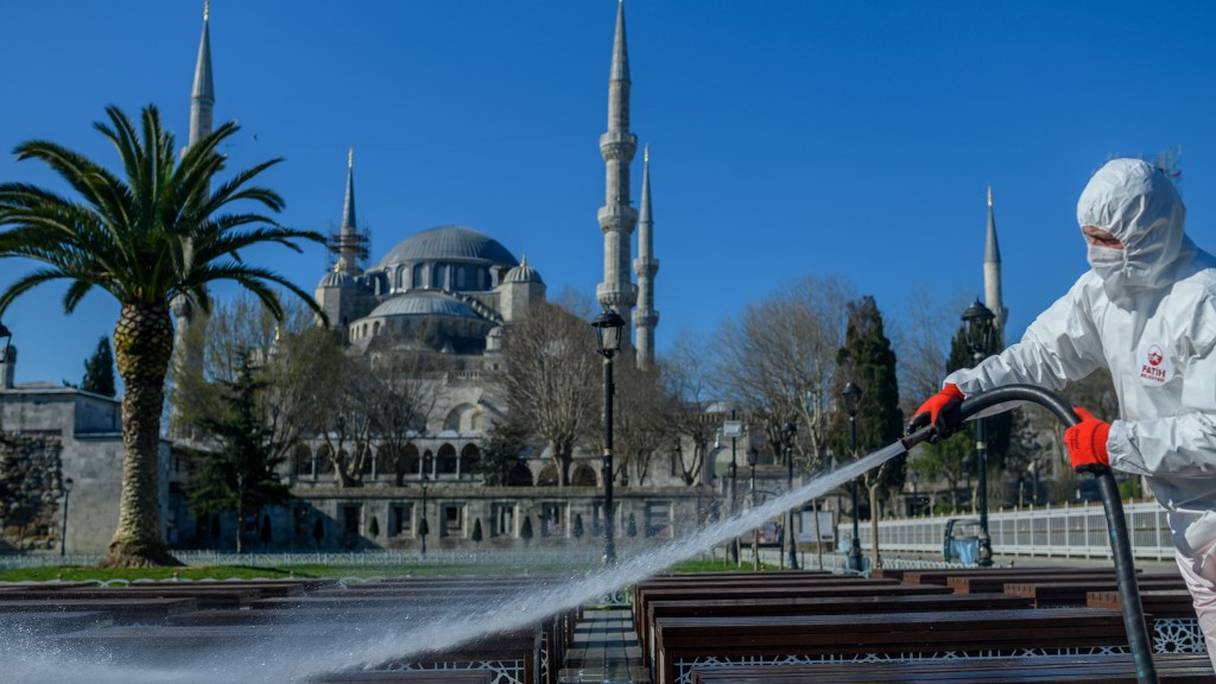 Un employé de la municipalité de Fatih désinfecte la place Sultanhamet à Istanbul avec la mosquée Bleue à l'arrière pour prévenir la propagation du COVID-19, le 21 mars 2020.

