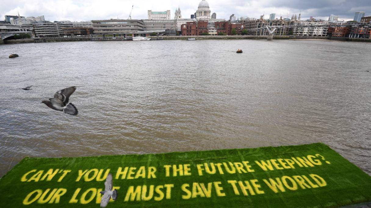 Cette bannière géante, tapis d'herbe vivante, enjoint les gouvernements d'agir maintenant, à l'approche de la COP26. Ce message environnemental a été installé par les activistes climatiques d'Extinction Rebellion sur la Tamise, dans le centre de Londres, le 25 juin 2021.
