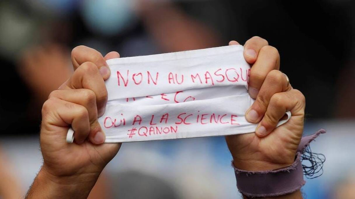 Un manifestant brandit un masque de protection sur lequel il a inscrit "non au masque, oui à la science", le 29 août 2020 à Paris. 
