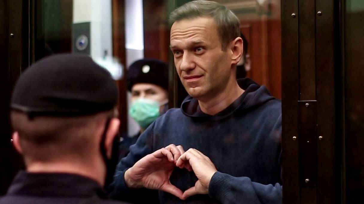 Le chef de l'opposition russe Alexeï Navalny joint ses mains et forme un cœur depuis l'intérieur d'une cellule de verre, lors d'une audience au tribunal à Moscou, le 2 février 2021.
