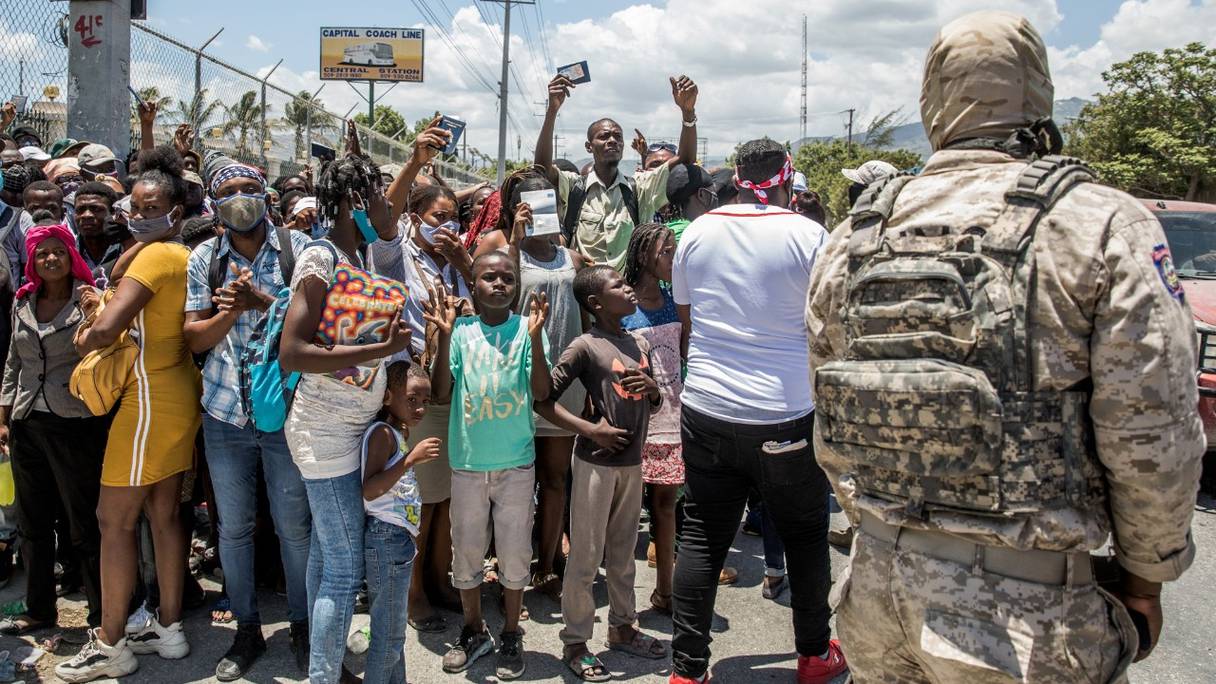 La police regarde des citoyens haïtiens se rassembler devant l'ambassade des Etats-Unis à Tabarre, en Haïti, le 10 juillet 2021, demandant l'asile après l'assassinat du président Jovenel Moïse, expliquant qu'il y a trop d'insécurité dans le pays.
